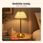 The Gem lamp on a bedside table next to a book and mug