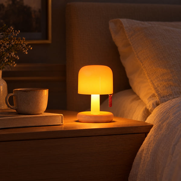 The Toadstool mushroom lamp glowing on a bedside table